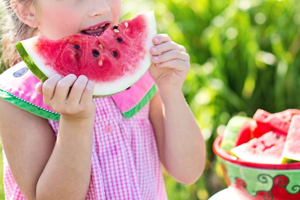 Girl Eating Sliced Watermelon Fruit Beside Table Outdoors