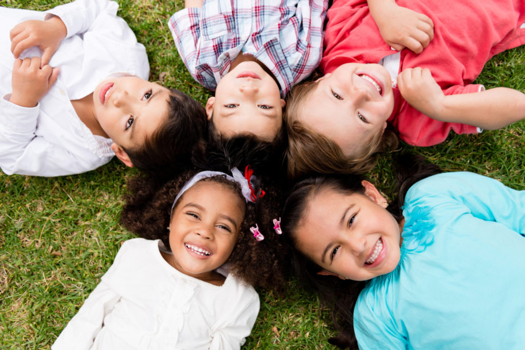 young kids lying on the floor in a circle shape with heads in the middle