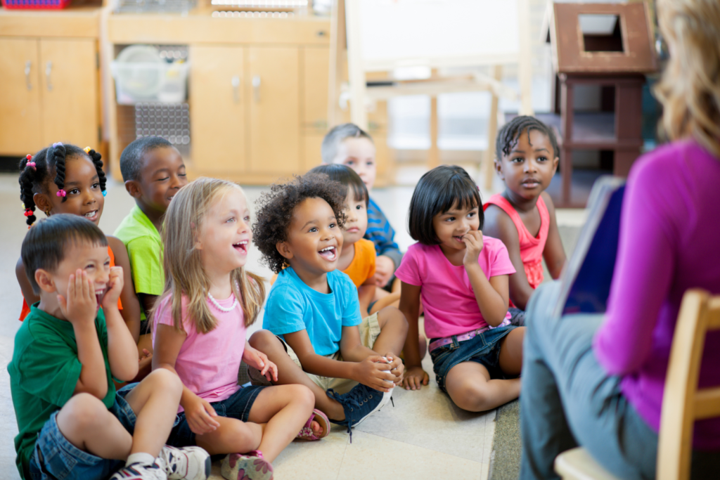 group of pre school children listening to a teacher reading a book